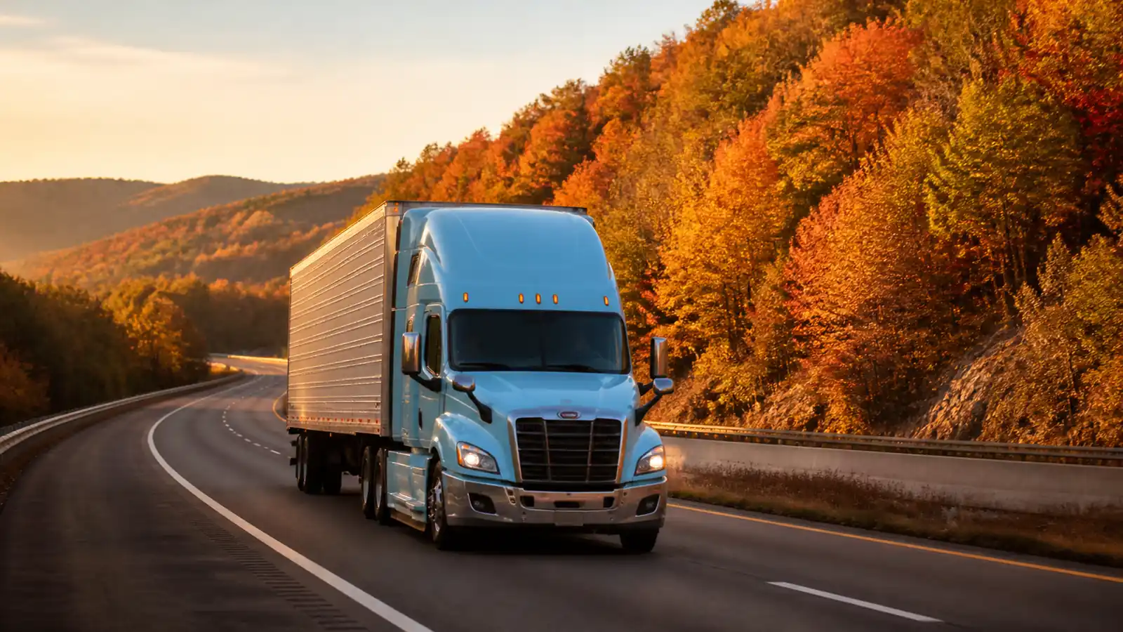 Sky-blue unbranded semi on a rolling upstate New York highway framed by autumn maples